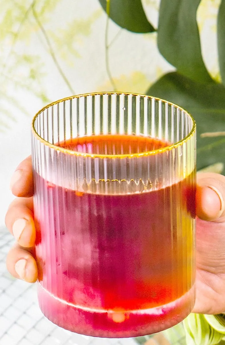 A ribbed glass of deep red Flavor Aid Singles To Go drink held in a hand