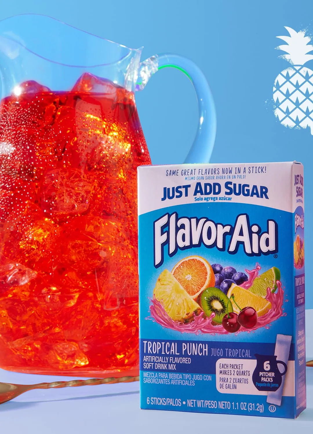 A glass pitcher of red Flavor Aid Tropical Punch over ice beside a Pitcher Packs carton